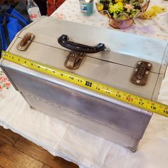 an old metal box with a measuring tape on it sitting on top of a table