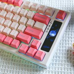 a pink and white computer keyboard sitting on top of a table next to a flower