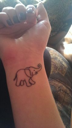 an elephant tattoo on the wrist of a woman's left hand, with black ink