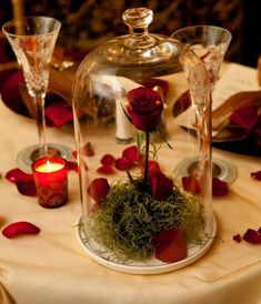 a glass clochet with flowers and moss on it sitting on top of a table