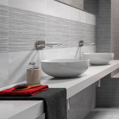 two white bowls sitting on top of a counter next to each other in a bathroom