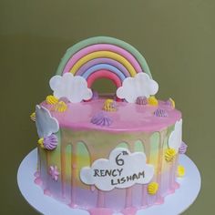 a birthday cake decorated with rainbows and clouds