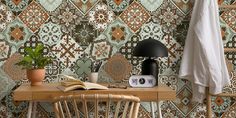 a wooden table topped with a lamp next to a wall covered in colorful tile tiles