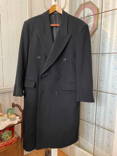 This handsome coat from Moore's is made from 70 per cent wool and 30 per cent polyester in classic navy blue. It has the original buttons on the front and cuffs, two outer pockets and one inner pocket, and is fully lined with dark blue silky lining. Marked size 40 short. The measurements, taken with the coat lying flat, are: shoulder to shoulder, 19 inches; armpit to armpit, 22 inches; sleeves, 24 inches; length, 47  inches; bottom edge, 38 inches. In very good condition. Classic Black Double-breasted Peacoat, Formal Wool Double-breasted Peacoat, Black Double-breasted Peacoat For Formal Occasions, Classic Long Peacoat With Double-breasted Fastening, Classic Long Peacoat With Double-breasted Buttons, Long Wool Coat For Formal Occasions, Formal Long Peacoat With Double Button Closure, Navy Wool Pea Coat For Formal Occasions, Classic Long Winter Blazer