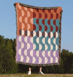 a person standing in front of a large blanket with circles on it and fringes around the edges