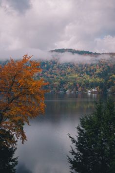 a lake surrounded by trees with clouds in the background