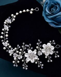 a close up of a necklace with flowers and pearls on the neck, next to a blue rose