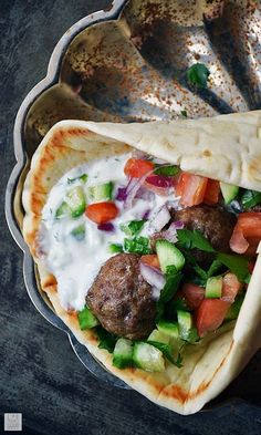 two pita breads with meatballs, vegetables and sauce in them on a plate