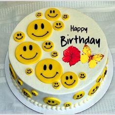 a white cake with yellow smiley faces on it's side and the words happy birthday written in red