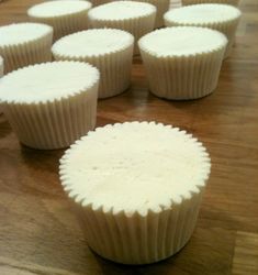 several white cupcakes sitting on top of a wooden table