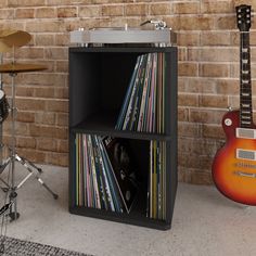 a record player and musical equipment are in front of a brick wall with a guitar