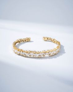 The Shimmer Audrey Diamond Bangle is the epitome of sophistication and refined style. It is exquisitely handcrafted with 18-karat spring gold wire to ensure both comfort and flexibility. Set with 3.06 carats of striking white diamond baguettes and accented with 0.42 carats of glistening round white diamonds, this bangle makes a profound statement of luxury. Whether it graces your wrist alone or is paired with other bracelets, its beauty is guaranteed to elevate your look. Details 18k yellow gold Elegant Yellow Gold Crystal Bracelet For Formal Occasions, Luxury Gold Baguette Cut Bracelet, Luxury Yellow Gold Crystal Bracelet For Formal Occasions, Formal Yellow Gold Crystal Bangle Bracelet, Formal Yellow Gold Bangle Crystal Bracelet, Formal Luxury Yellow Gold Crystal Bracelet, Luxury Gold-plated Tennis Bracelet, Modern Gold Bracelet With Baguette Cut, Modern Gold Baguette-cut Bracelet