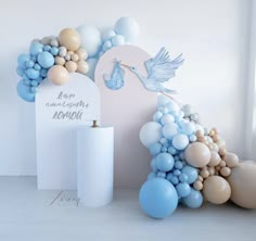 balloon arch with stork and baby shower items in blue, beige and white