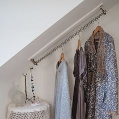 three different dresses hanging on clothes racks in a room