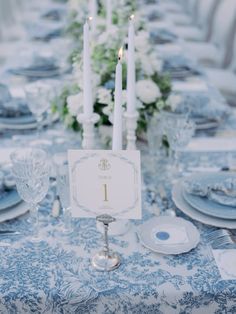 the table is set with blue and white linens, silverware, and candles