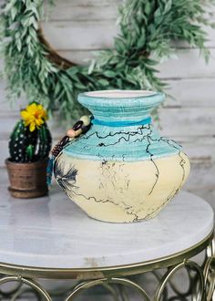 a blue and white vase sitting on top of a table next to a potted plant