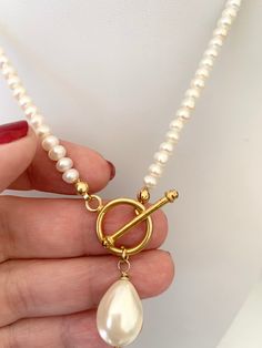 a person holding a necklace with pearls and a pair of scissors in their left hand