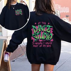 a woman walking down the street wearing a black sweatshirt with dance studio written on it