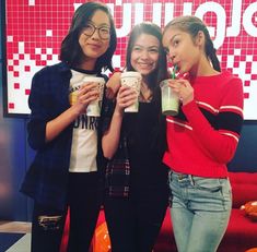 three girls are posing for the camera while holding cups with drinks in their hands and smiling