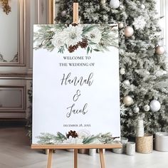 a welcome sign sitting in front of a christmas tree with pine cones and white flowers