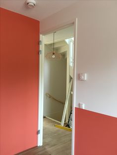 an open door leading into a room with pink walls and wood flooring on the other side