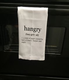 a white tea towel hanging on the side of an oven door saying, hangry