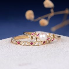 two gold rings with pink and white stones on them, one is in front of the other