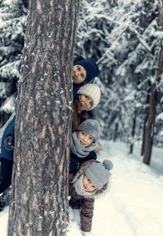 a group of people standing next to a tree in the snow