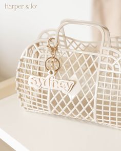 a white purse sitting on top of a table next to a mirror with a keychain hanging from it