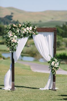 an outdoor ceremony setup with white flowers and greenery