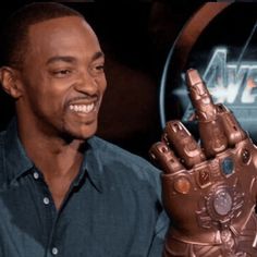 the man is holding up his hand in front of an iron man sign and smiling