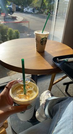 a person holding up a cup of coffee in front of a table with a view