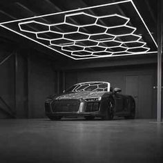 a black and white photo of a car parked in a garage with the lights on