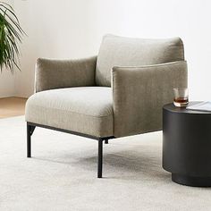 a living room with a chair, table and potted plant