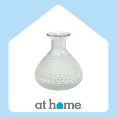 a clear glass vase sitting on top of a blue and white sign that says at home