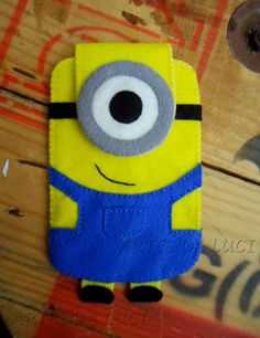 a yellow and blue minion cell phone case sitting on top of a wooden table