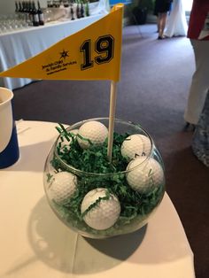 a glass bowl filled with golf balls sitting on top of a white tablecloth covered table