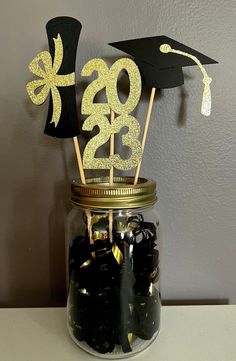 a mason jar filled with black and gold graduation decorations