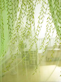 green leaves are hanging from the sheer curtains in this room with white furniture and windows