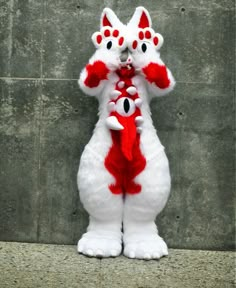 two white and red stuffed animals standing next to each other with their arms around one another