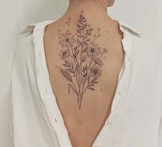 a woman's back tattoo with flowers and leaves on her left side ribcage