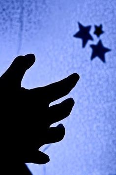 a person's hand is silhouetted against a blue background with stars