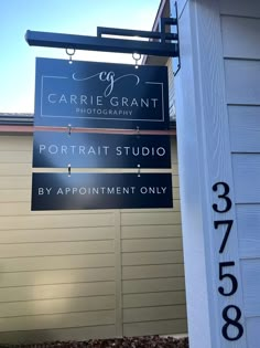 a sign for a portrait studio hanging from the side of a building in front of a house