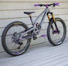 a bike is parked on the side of a building with purple accents and yellow spokes