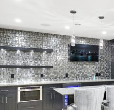 a large kitchen with grey cabinets and marble counter tops, along with bar stools