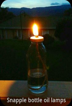 a lit candle sitting in a glass jar on a table with the words, snapple bottle oil lamps