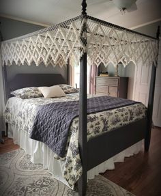 a four poster bed with crocheted bedspread and pillows