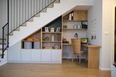 a room with a desk, bookshelf and stairs