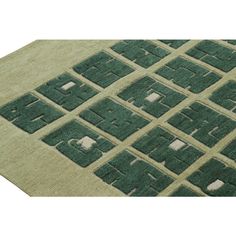 a green rug with squares and rectangles on the top in various shades of green