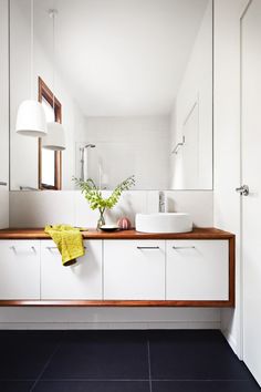 a white bathroom with two sinks and a large mirror on the wall next to it